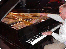 Chuck Howes working on a piano